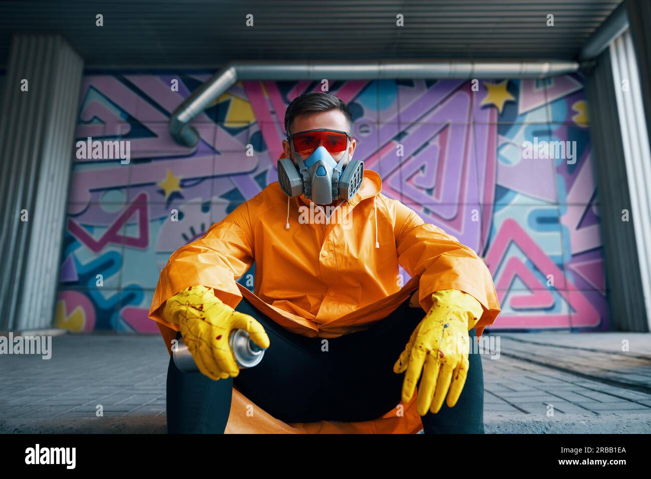 Graffiti painter rest near the wall with his paintings looking to