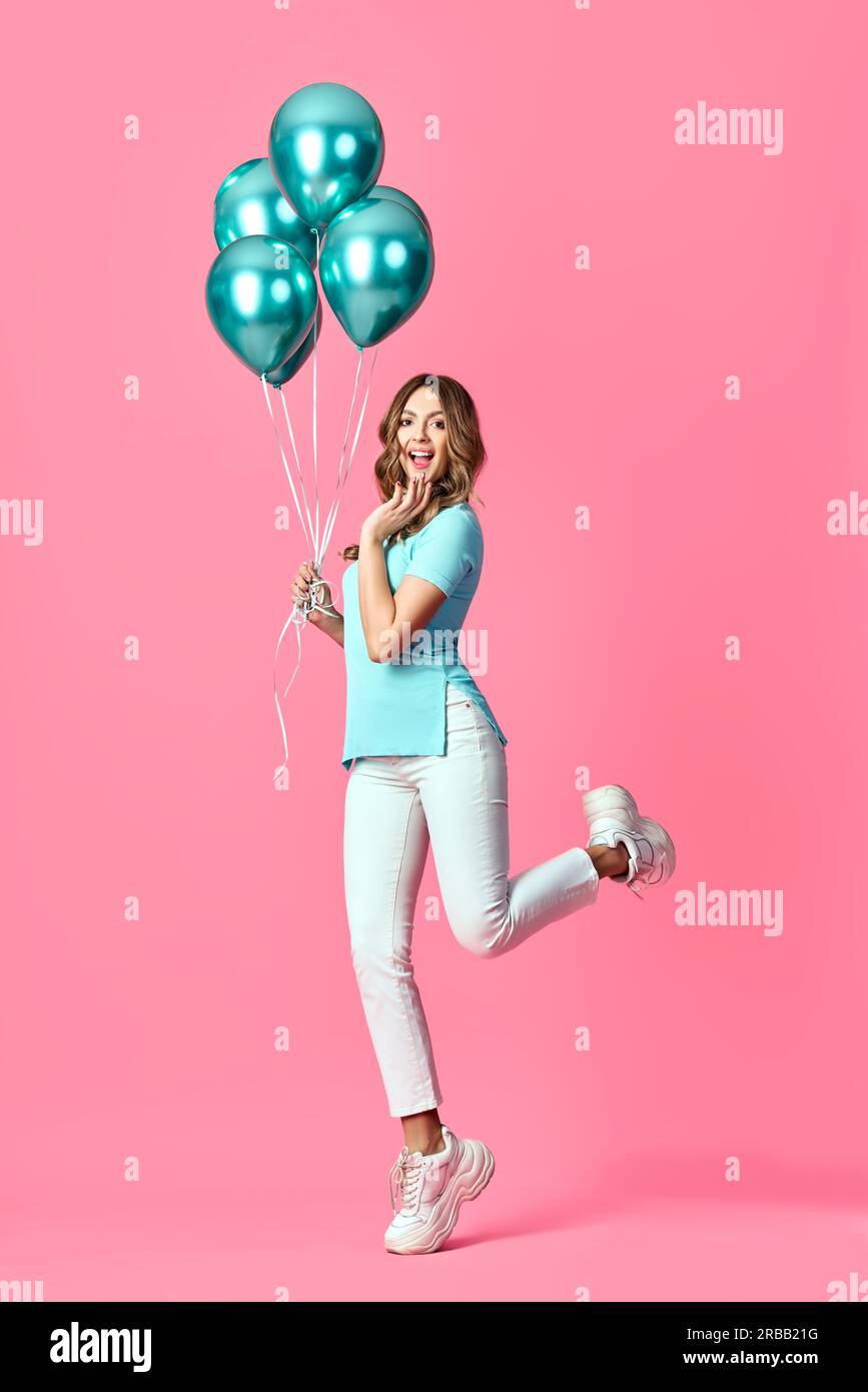 Full length portrait of happy pretty woman with blue balloons in hands on pink background. Party concept Stock Photo