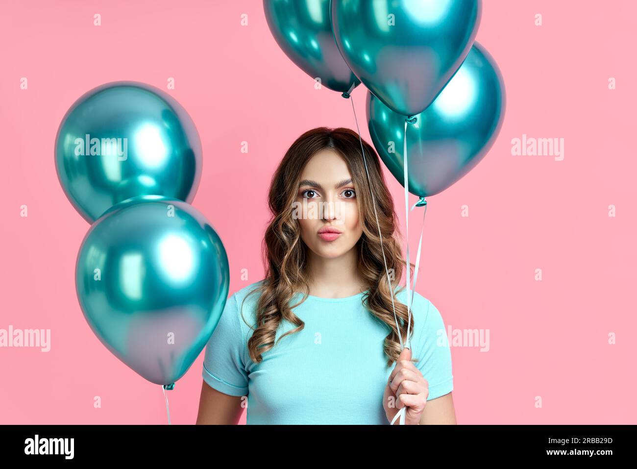 Close up portrait of happy pretty woman with blue balloons in hands on pink background. Party concept Stock Photo