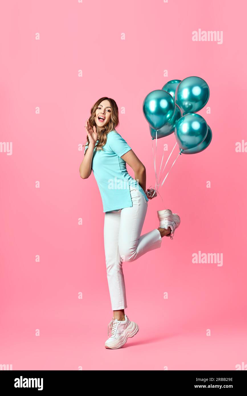 Full length portrait of happy pretty woman with blue balloons in hands on pink background. Party, emotions concept Stock Photo