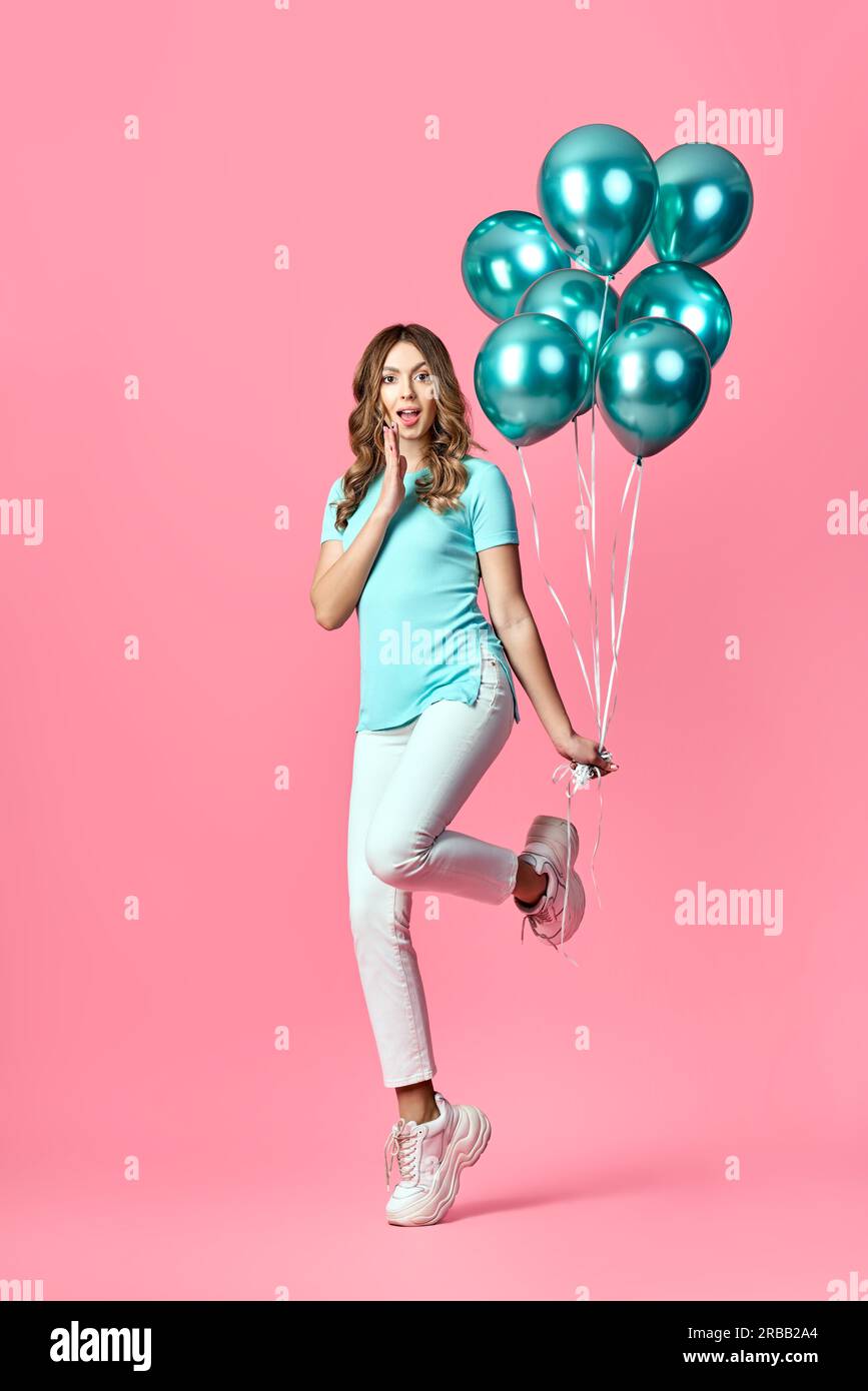 Full length portrait of happy surprised woman with blue balloons in hands on pink background. Party, emotions concept Stock Photo