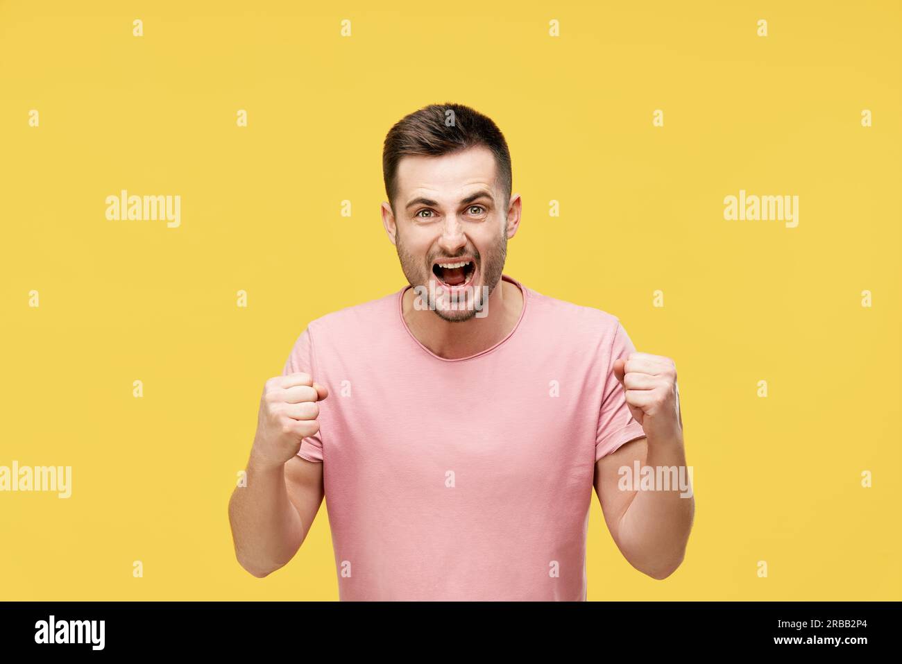 Young man celebrating with winner gesture on yellow background. victory, triumph and emotions concept Stock Photo
