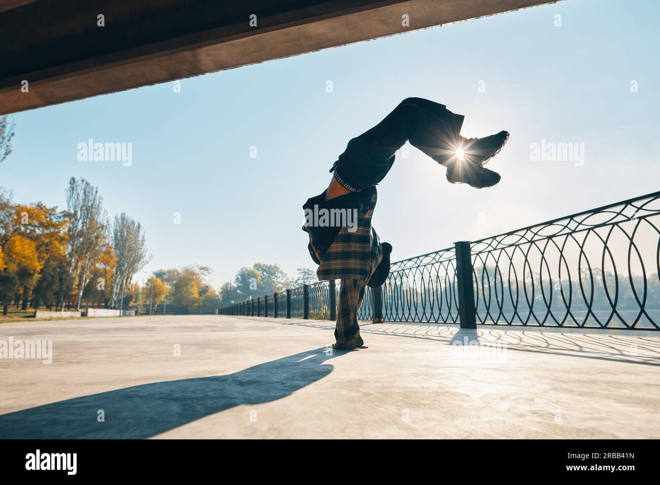 Young man break dancer dancing on urban background performing acrobatic stunts. Street artist breakdancing outdoors Stock Photo