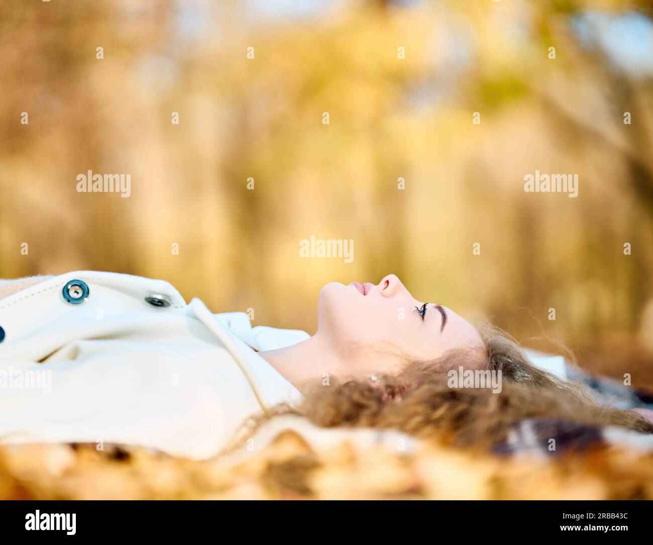 Autumn portrait of happy smiling young woman relaxing lying in fall yellow leaves with copy space. Happy autumn, rest, female beauty concept Stock Photo