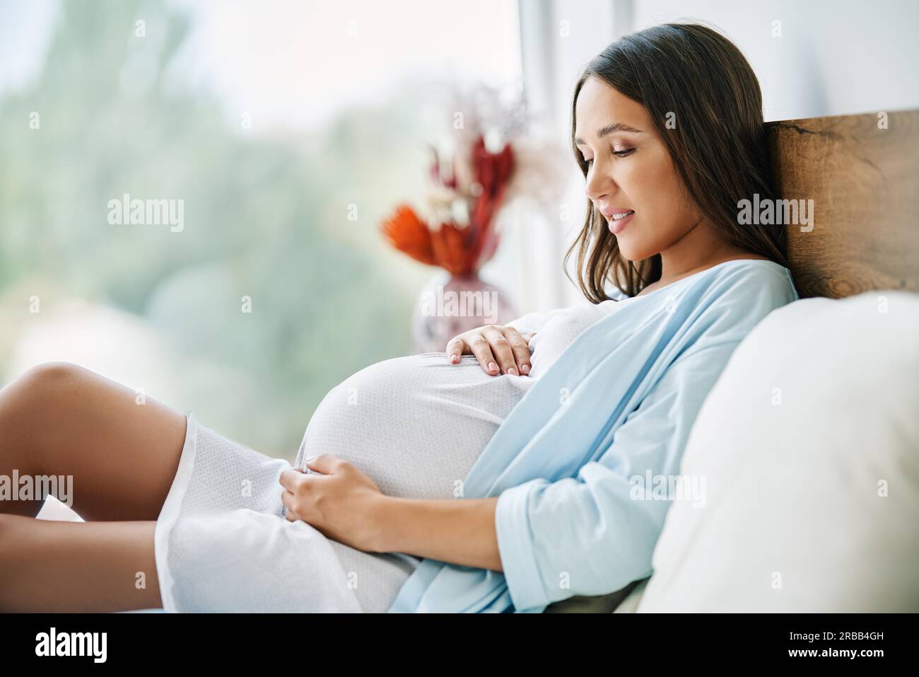 Portrait of happy pregnant woman lying in bed and touching her belly at home. Motherhood, people concept. Tender mood photo of pregnancy Stock Photo
