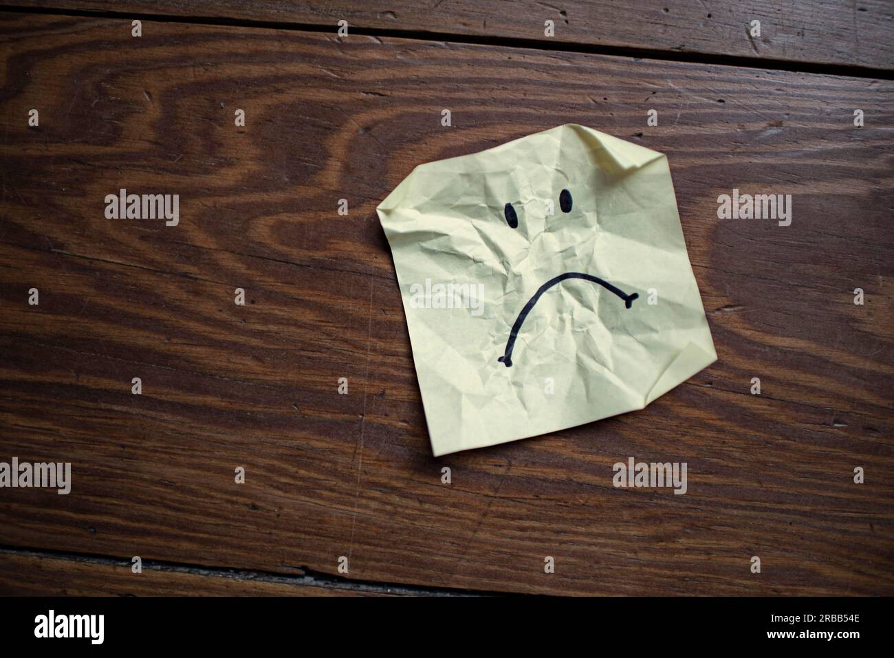 Crumpled note with bad-tempered smiley face Stock Photo