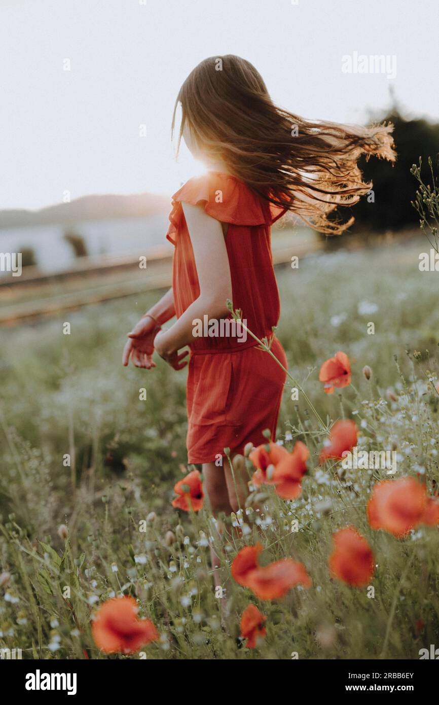 Girl in a red dress in a poppy meadow Stock Photo - Alamy