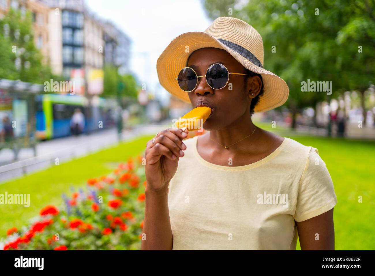 African black ethnicity woman eating a mango ice cream in the city in summer Stock Photo