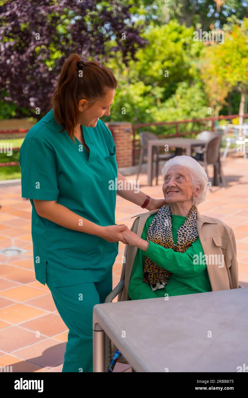 An older or mature woman with the nurse in the garden of a nursing home or retirement home Stock Photo