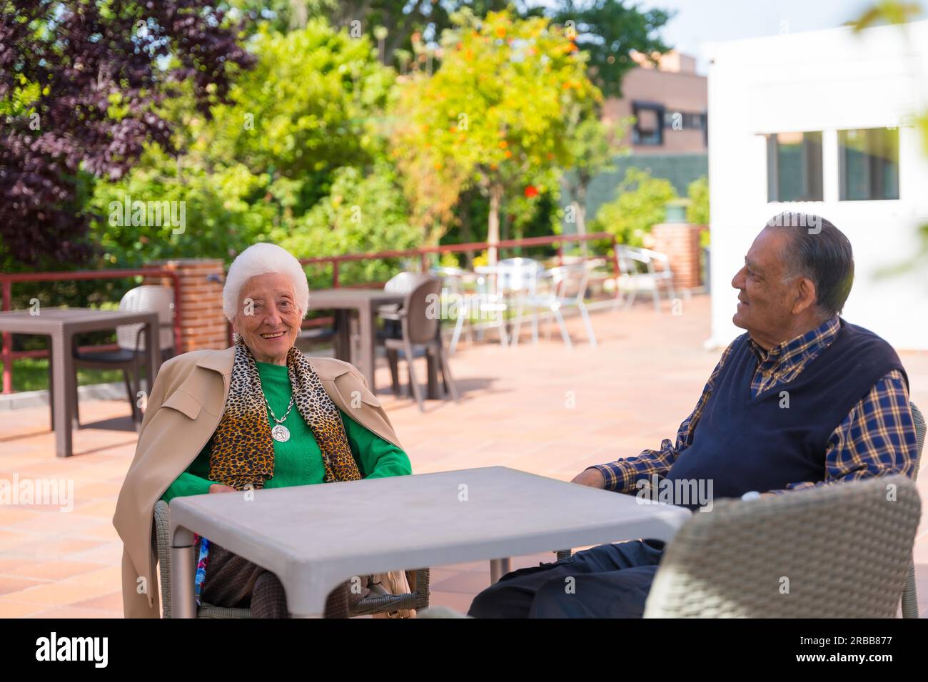 Two very cheerful elderly people in the garden of a nursing home, resting in the morning on a sunny summer day Stock Photo