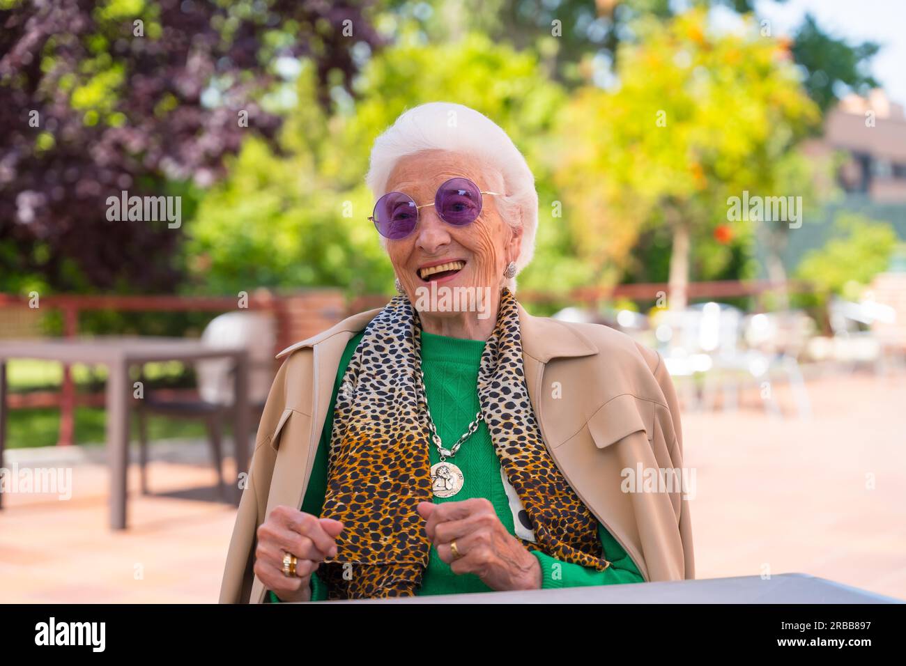 An elderly woman dancing in the garden of a nursing home or retirement home at a summer party wearing sunglasses Stock Photo