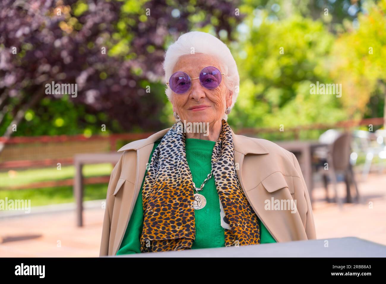 An elderly woman in the garden of a nursing home or retirement home at a summer party wearing sunglasses Stock Photo