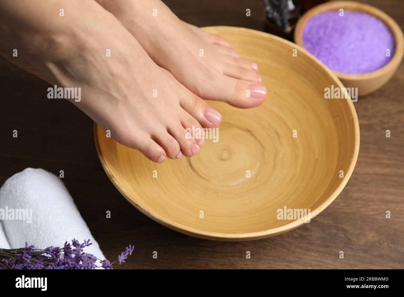 Woman soaking her feet in bowl with water, closeup. Pedicure procedure