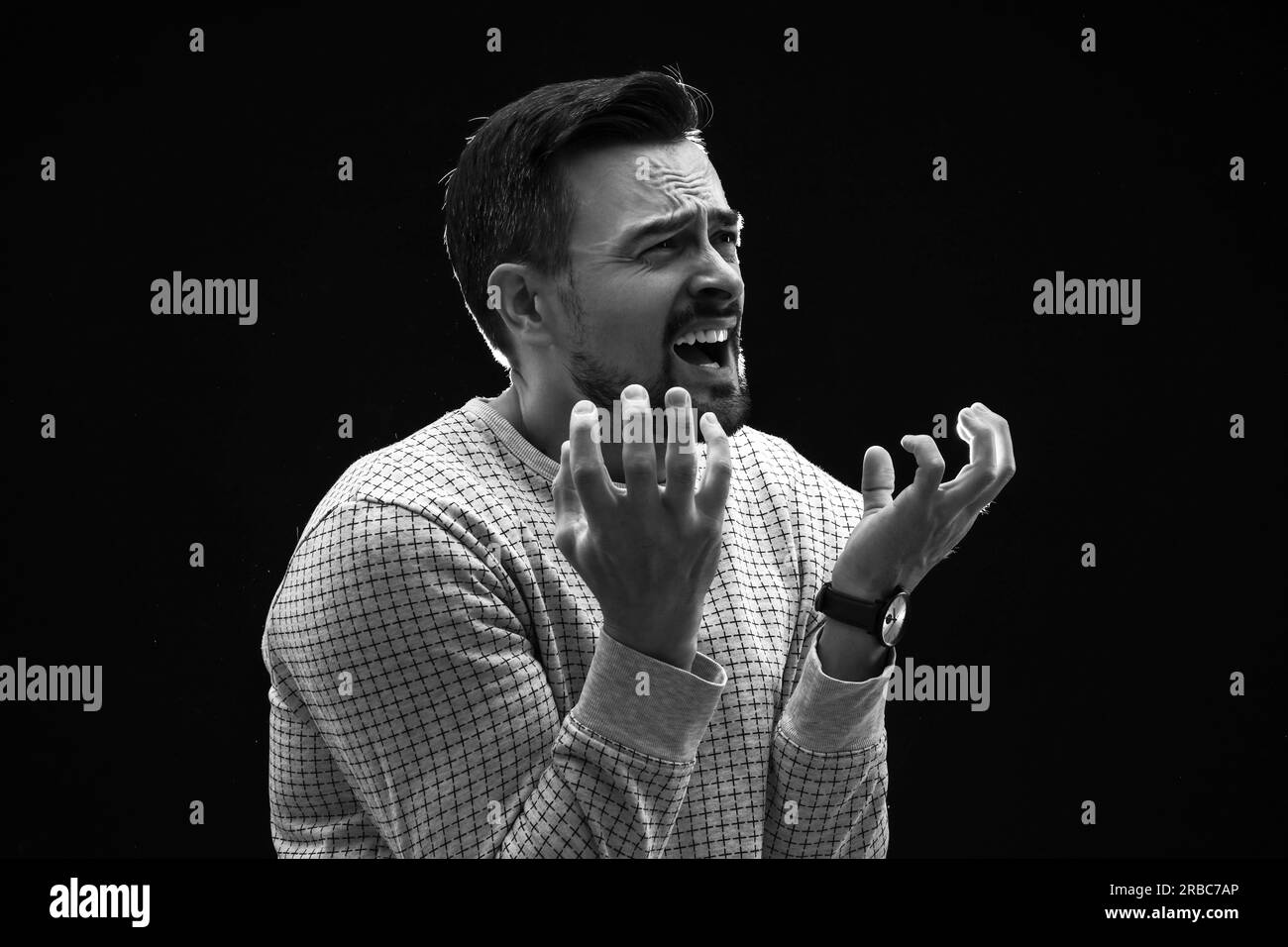 Young man having panic attack on black background Stock Photo - Alamy