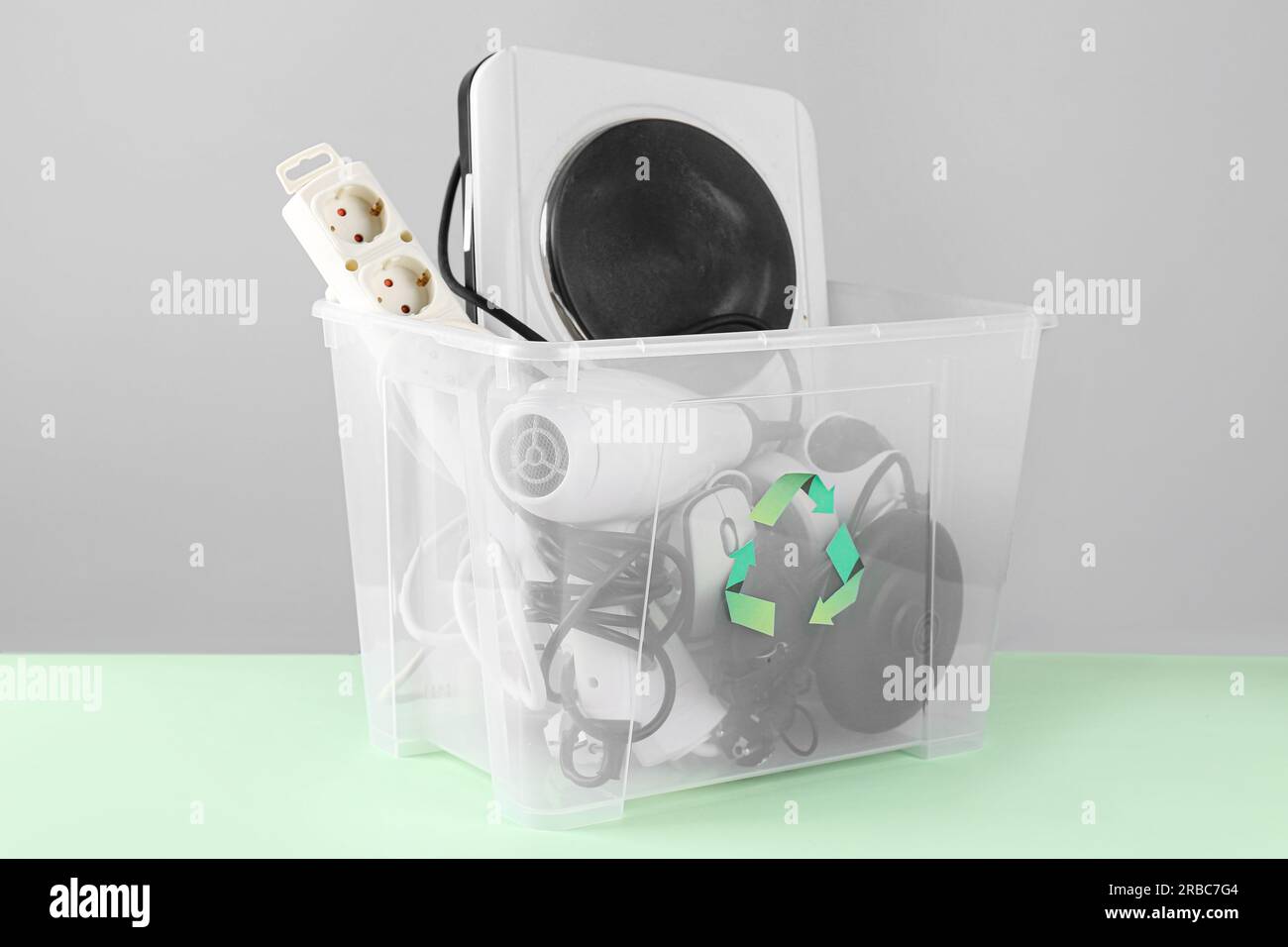 Recycle bin with different household appliances on green background