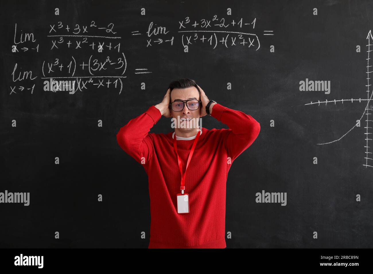 Stressed Math teacher near blackboard in classroom Stock Photo