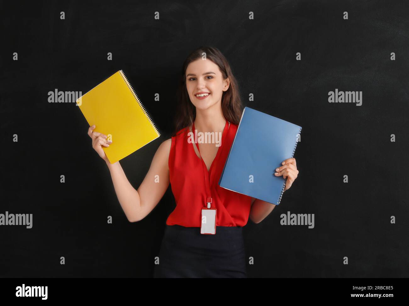 Instructor With Notebook Female teacher with notebooks near blackboard in classroom Stock Photo ...