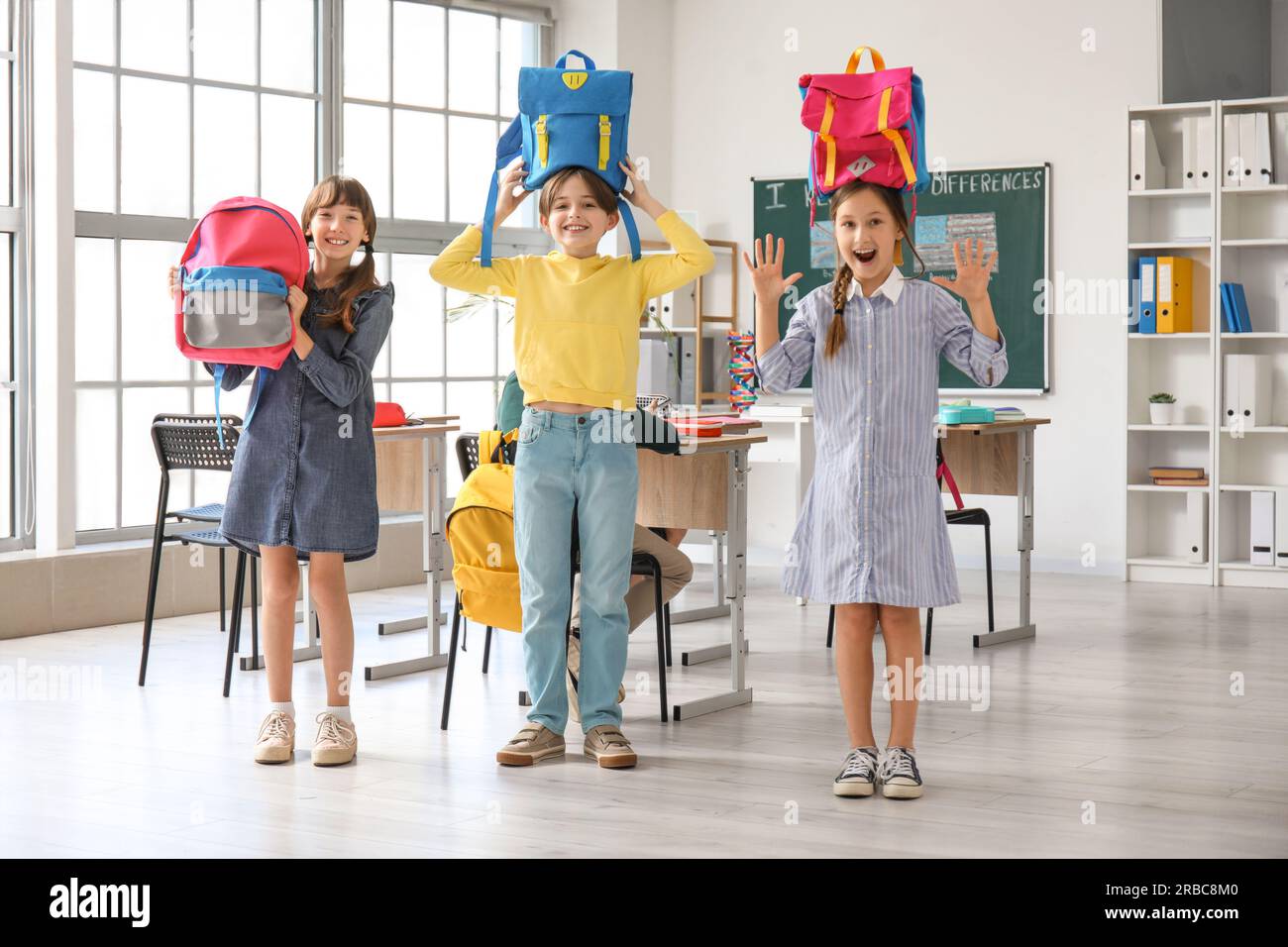 Little pupils with backpacks in classroom Stock Photo Alamy
