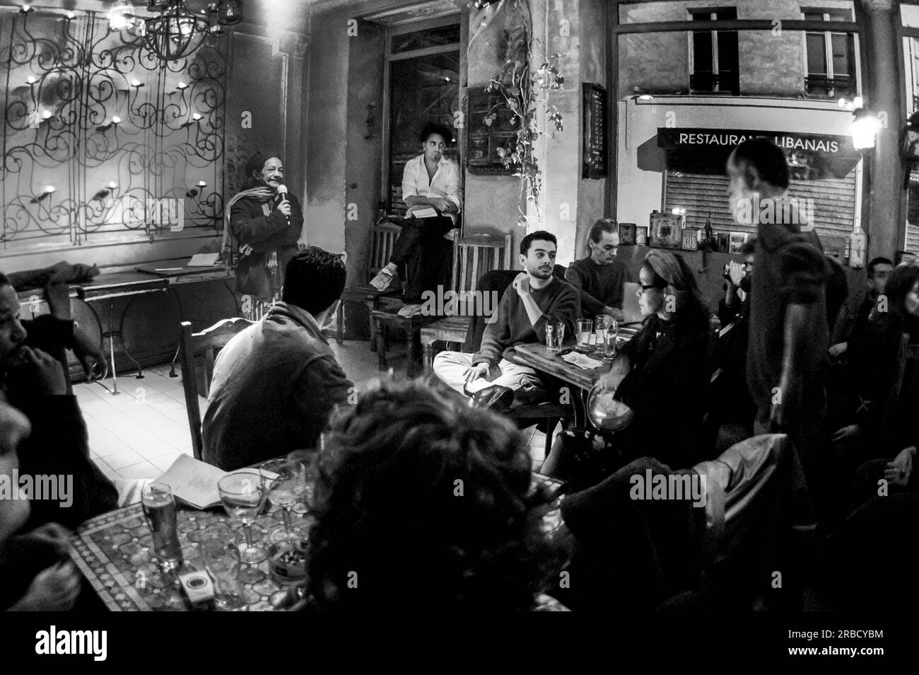 Paris, France, Crowd People Sharing Drinks in Parisian Bar, Cafe, Listening to 'Slam Poetry' Artist giving show, 'Lucioles Café', Night Stock Photo