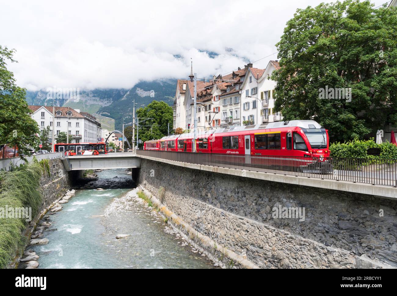 A Rhaetian Railway Ferrovia retica train alongside the river Plessur in Chur, Switzerland, Europe Stock Photo
