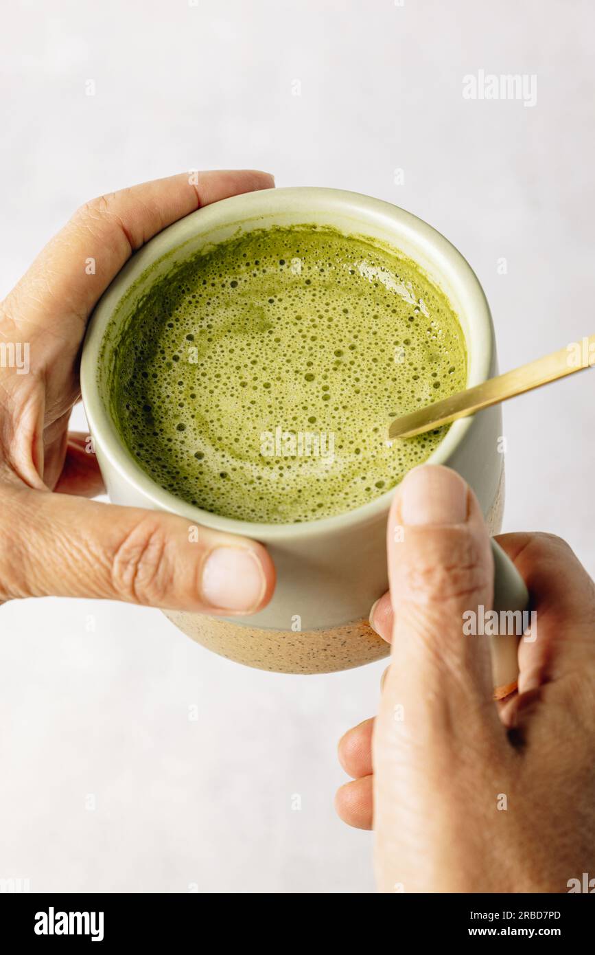 Top view of matcha latte: a tantalizing blend of green perfection, served with a golden spoon amidst a dusting of vibrant green powder. Stock Photo