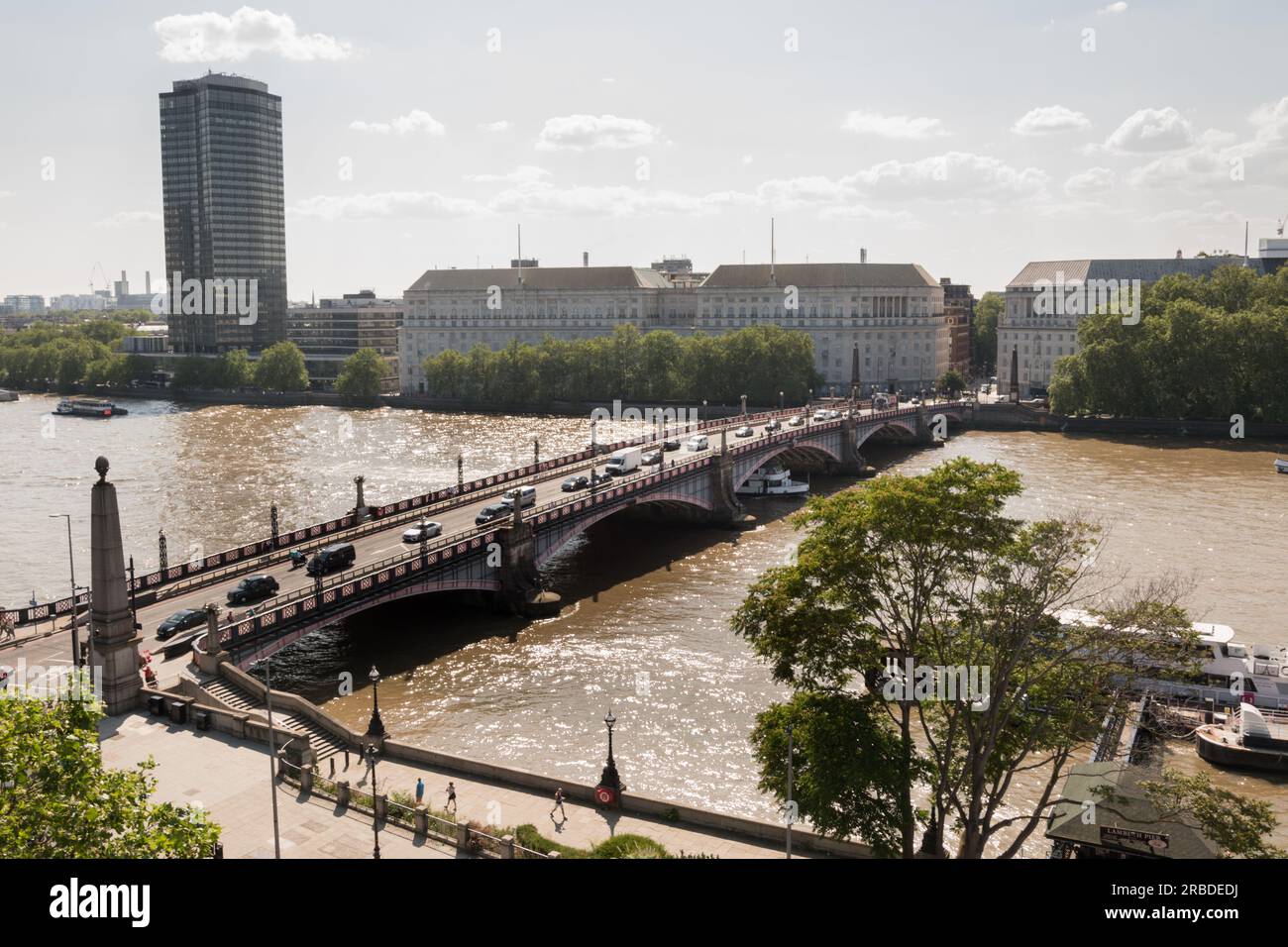 Southbound traffic passing across Lambeth Bridge with Thames House, Mi5 headquarters building on Millbank in the background, London, England, U.K. Stock Photo