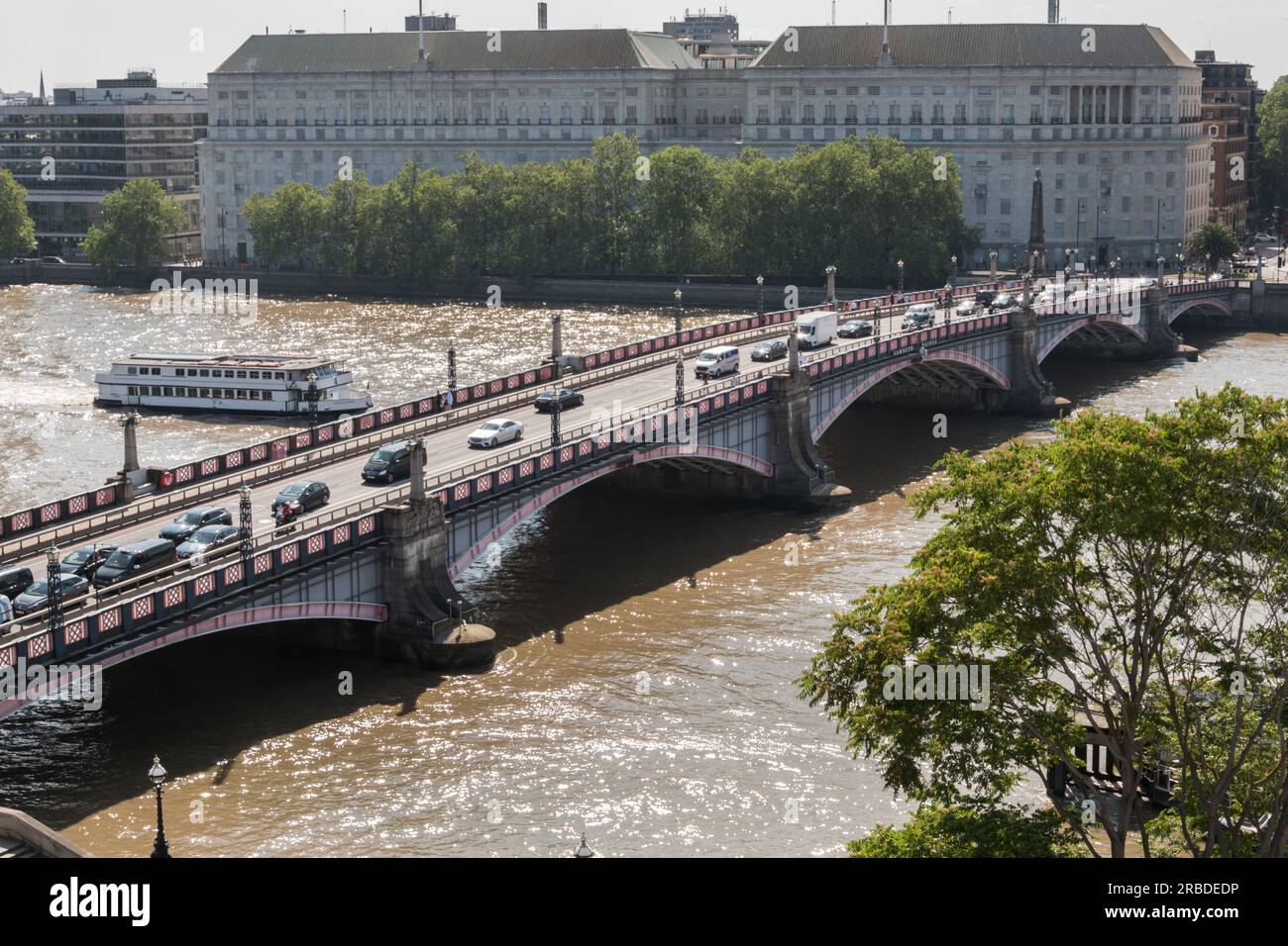 Southbound traffic passing across Lambeth Bridge with Thames House, Mi5 headquarters building on Millbank in the background, London, England, U.K. Stock Photo