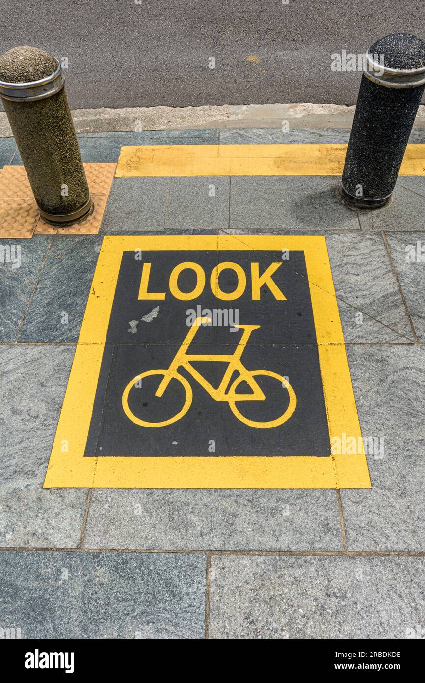 A warning sign indicating to watch out for cyclists passing when stepping onto the road in Singapore Stock Photo