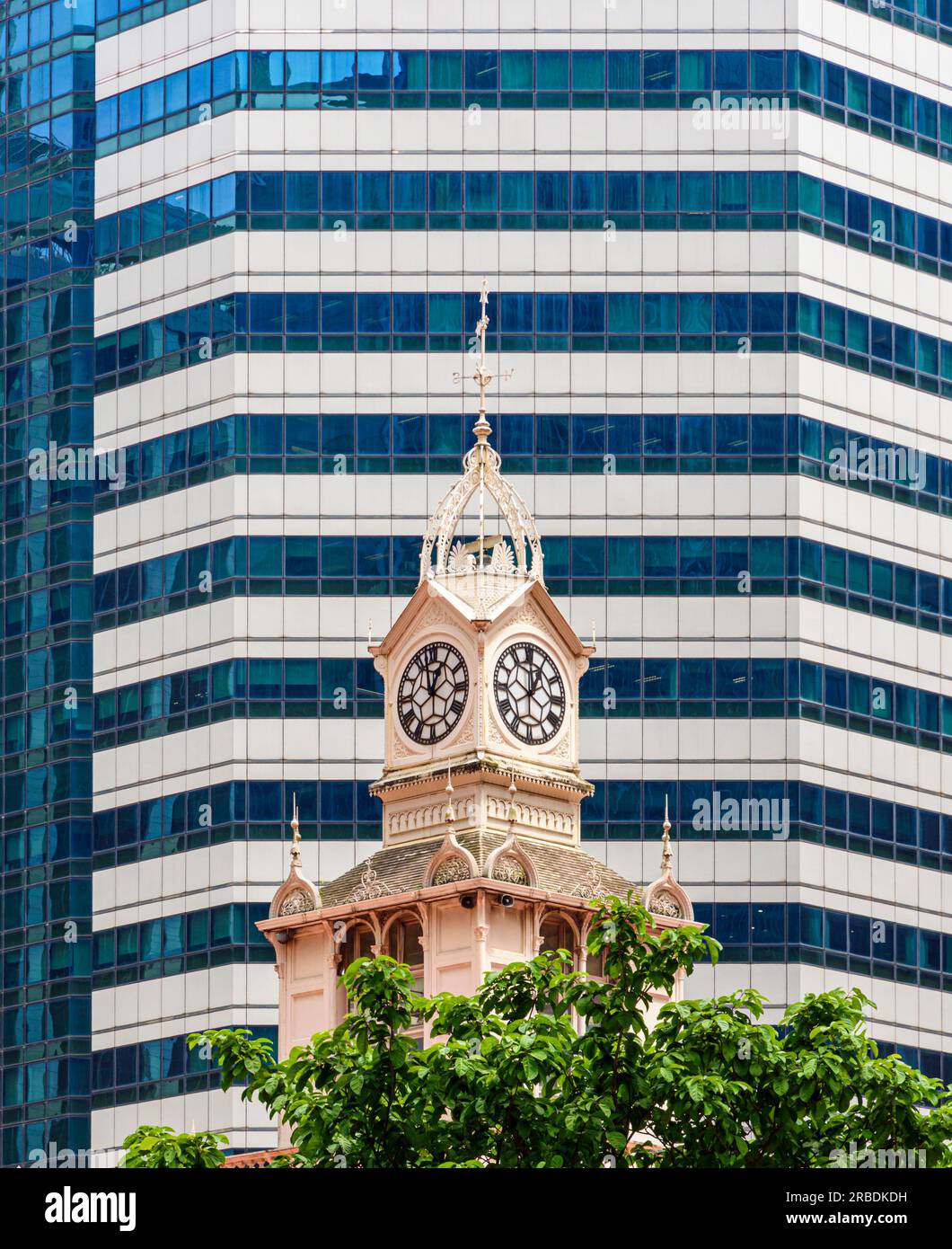 Old and new Singapore with the Lau Pa Sat clocktower against a modern office block behind Stock Photo