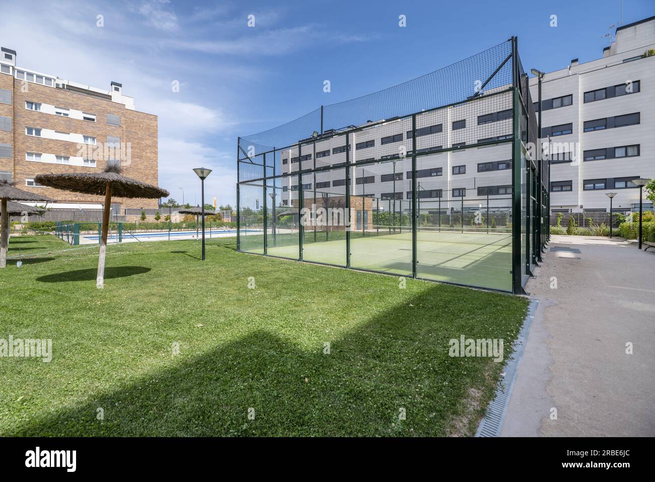 Garden areas with a swimming pool, straw umbrellas and a tennis court
