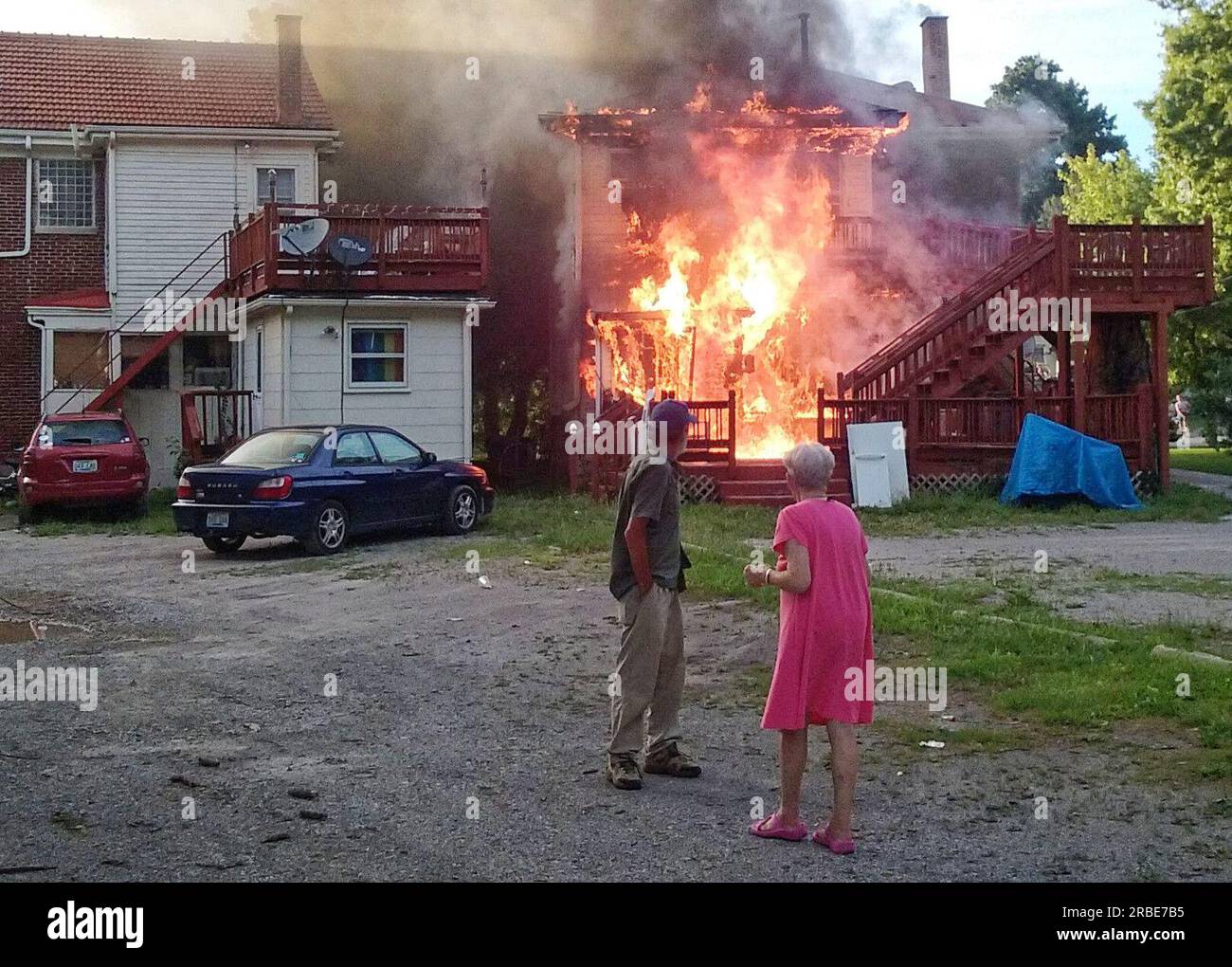 An unidentified man and woman watch as flames erupt from the back of a two-story house at 1006 Fontaine Rd. on the border between the Ashland Park and Chevy Chase neighborhoods on Sunday, July 10, 2016 in Lexington, Fayette County, KY, USA. No injuries were reported and the cause of the fire has not yet been determined. (Apex MediaWire Photo by Billy Suratt) Stock Photo