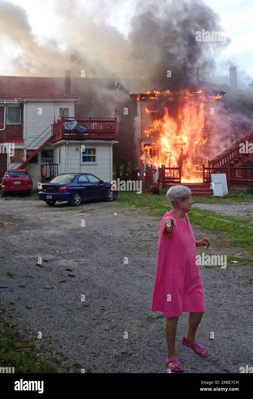 An unidentified woman walks away as flames erupt from the back of a two-story house at 1006 Fontaine Rd. on the border between the Ashland Park and Chevy Chase neighborhoods on Sunday, July 10, 2016 in Lexington, Fayette County, KY, USA. No injuries were reported and the cause of the fire has not yet been determined. (Apex MediaWire Photo by Billy Suratt) Stock Photo