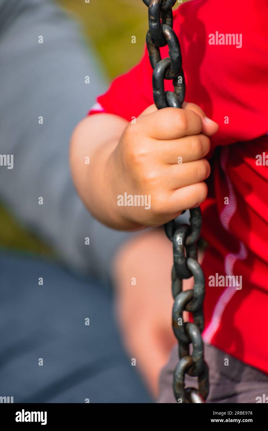 Closeup on a baby’s hand holding a chain, kid having fun playing on a