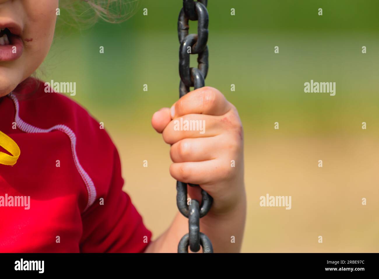 Closeup on a baby’s hand holding a chain, kid having fun playing on a