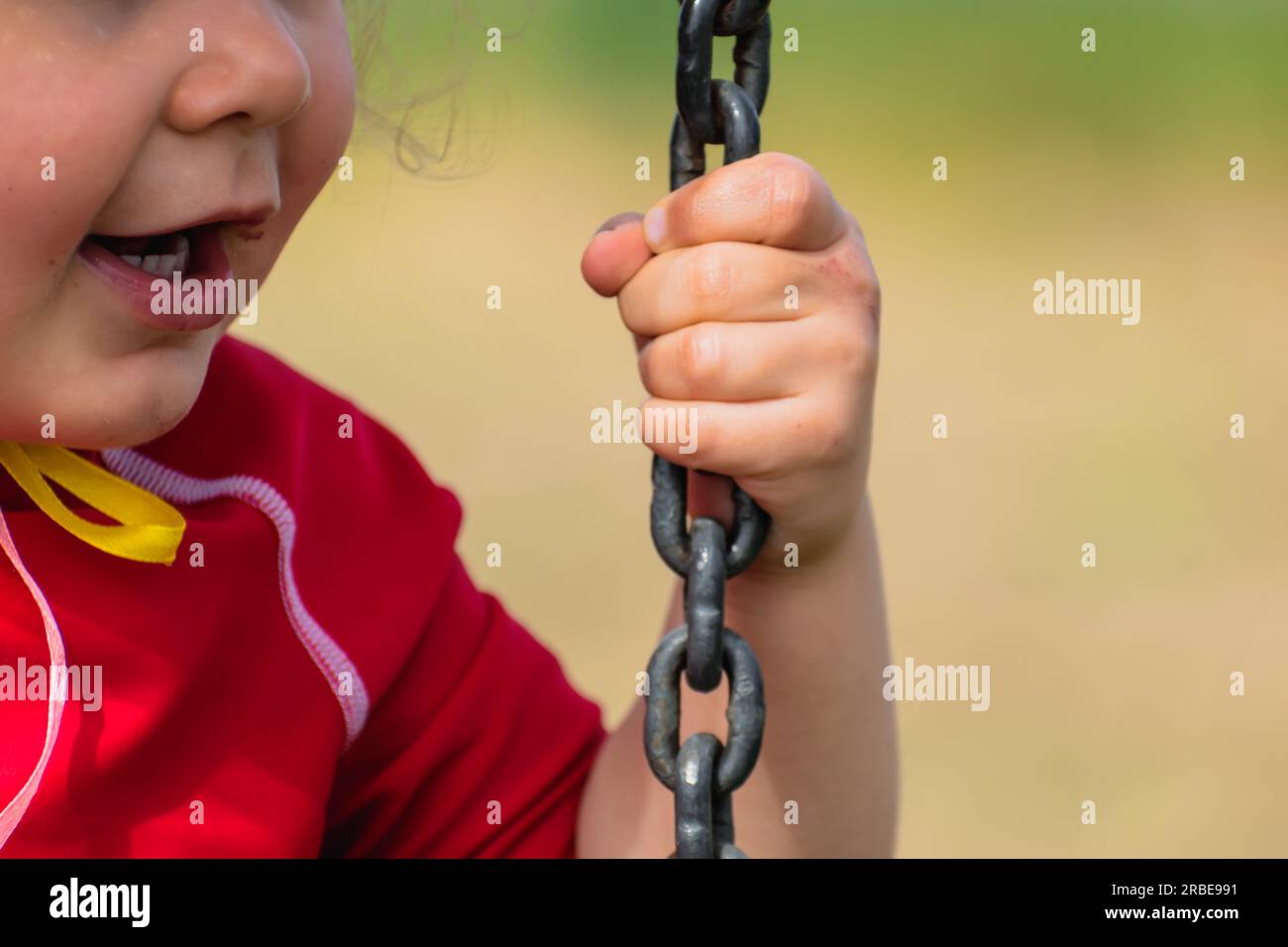 Closeup on a baby’s hand holding a chain, kid having fun playing on a