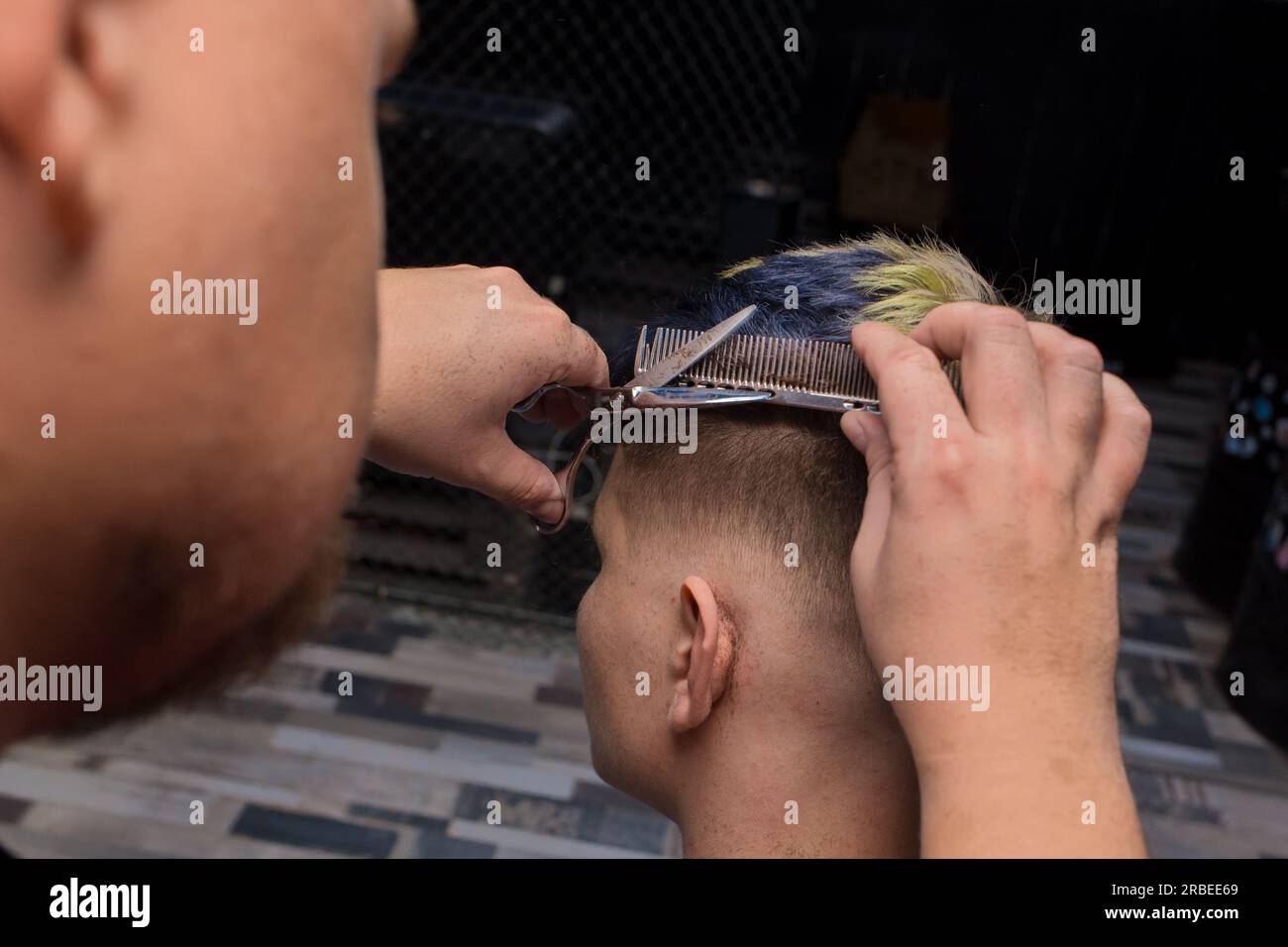 Hairdresser barber salon man cuts hair to a client guy at work with scissors and a comb professionally. Stock Photo