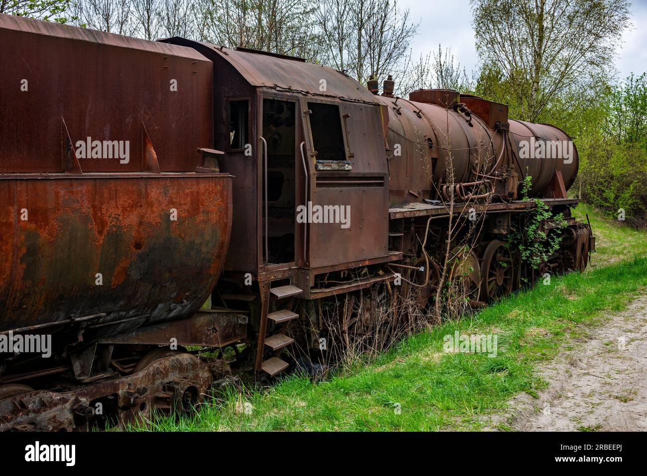 Rusted steem locomotive with coal car abandoned at train cemetary on old rail track. Stock Photo
