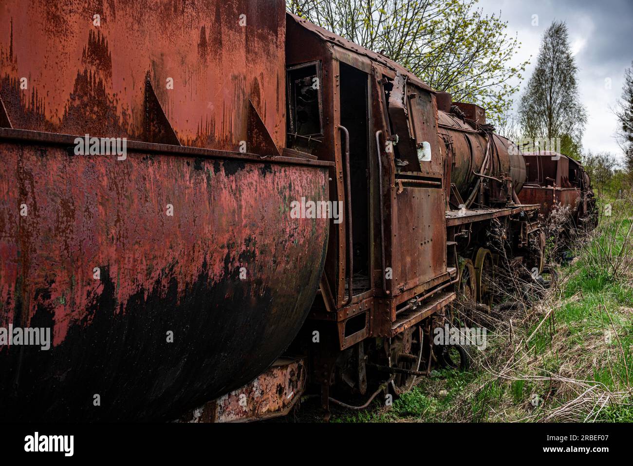 Rusted steem locomotive with coal car abandoned at train cemetary on old rail track. Stock Photo