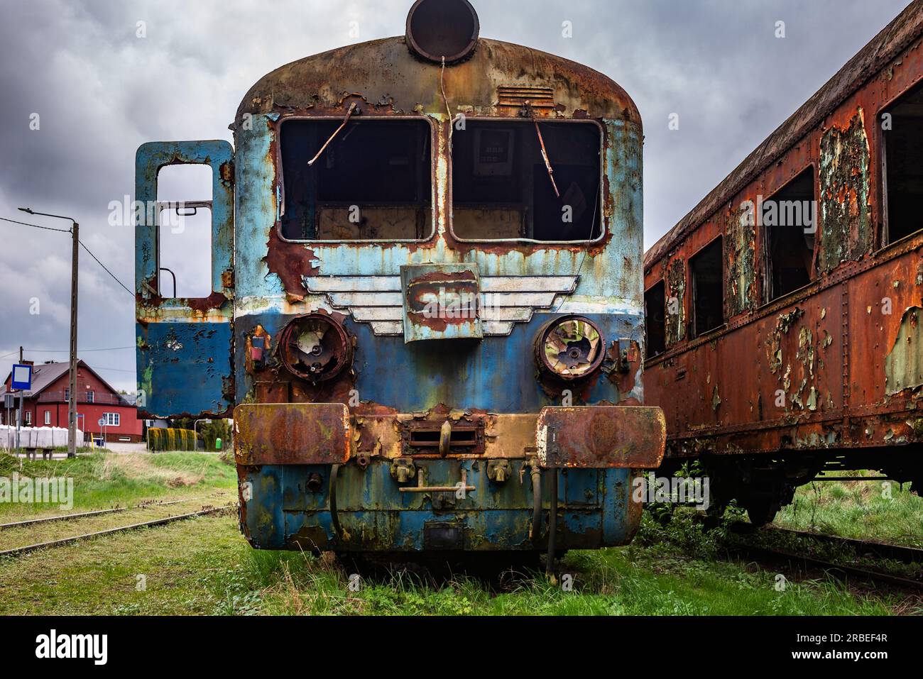 Old rusty electric multiple unit train decommissioned and abandoned on railway siding on green grassy field Stock Photo