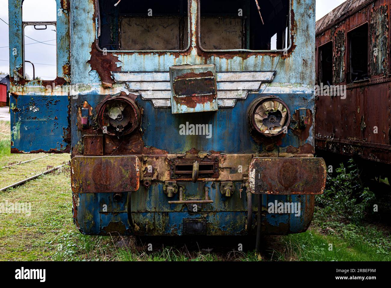Old rusty electric multiple unit train decommissioned and abandoned on railway siding on green grassy field Stock Photo