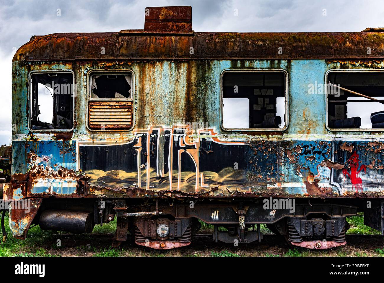 Old rusty electric multiple unit train decommissioned and abandoned on railway siding on green grassy field Stock Photo