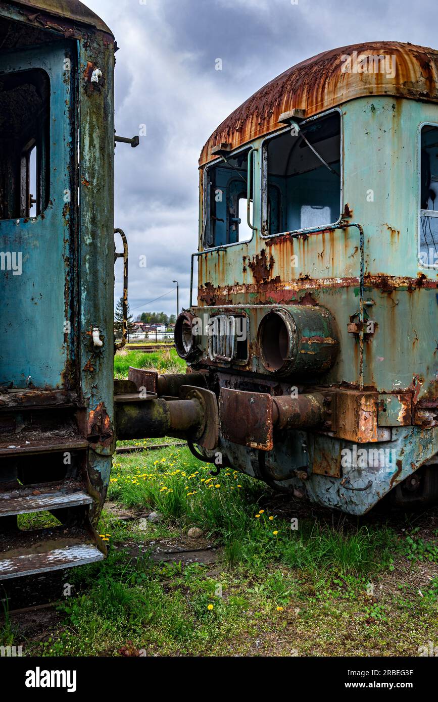 Old rusty passenger electric multiple unit train decommissioned and abandoned on railway siding on green grassy field Stock Photo