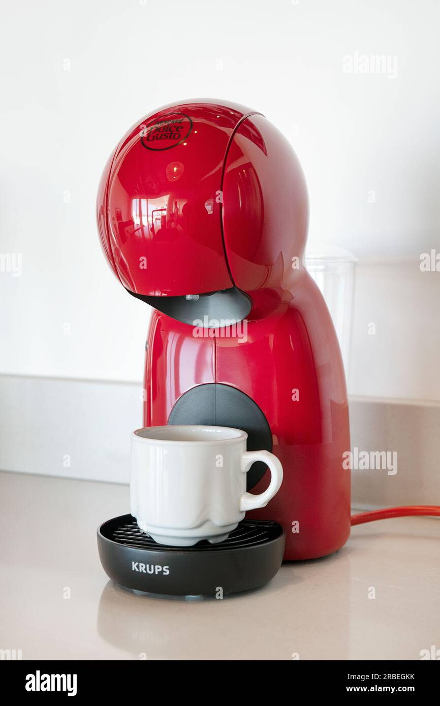 Nescafe Dolce Gusto Krups coffee machine in red color set on a kitchen counter, which uses a pre-packed coffee capsule system to make the hot beverage Stock Photo