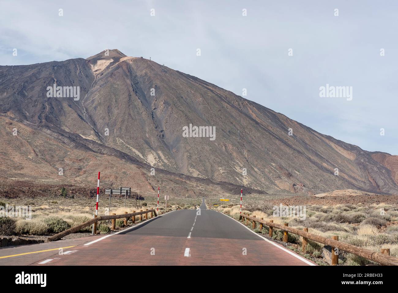Empty road surrounded by the arid volcanic landscape with the majestic peak Mount Teide known locally as Pico del Teide in front in Pico del Teide Stock Photo
