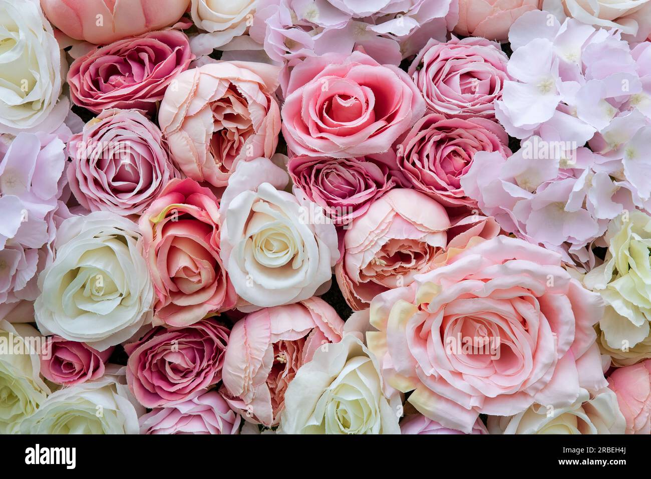 Artificial flowers such as peonies, hydrangeas and roses in pastel colors set closely together to form a beautiful and romantic background Stock Photo