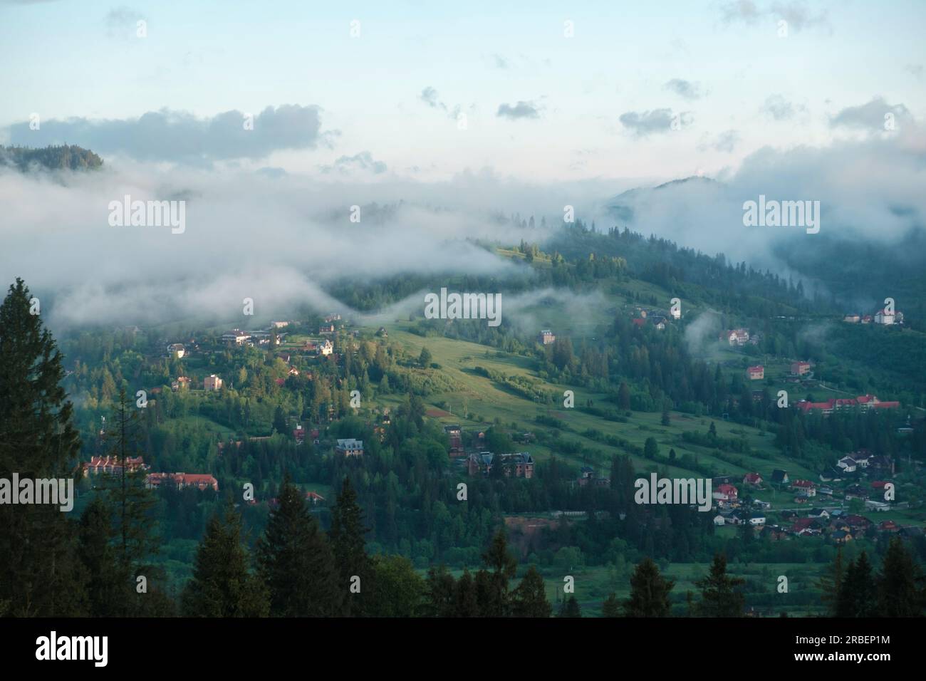 mountainous rural landscape at sunset. beautiful scenery with forests, hills and meadows in evening light. ridge with high peak in the distance Stock Photo