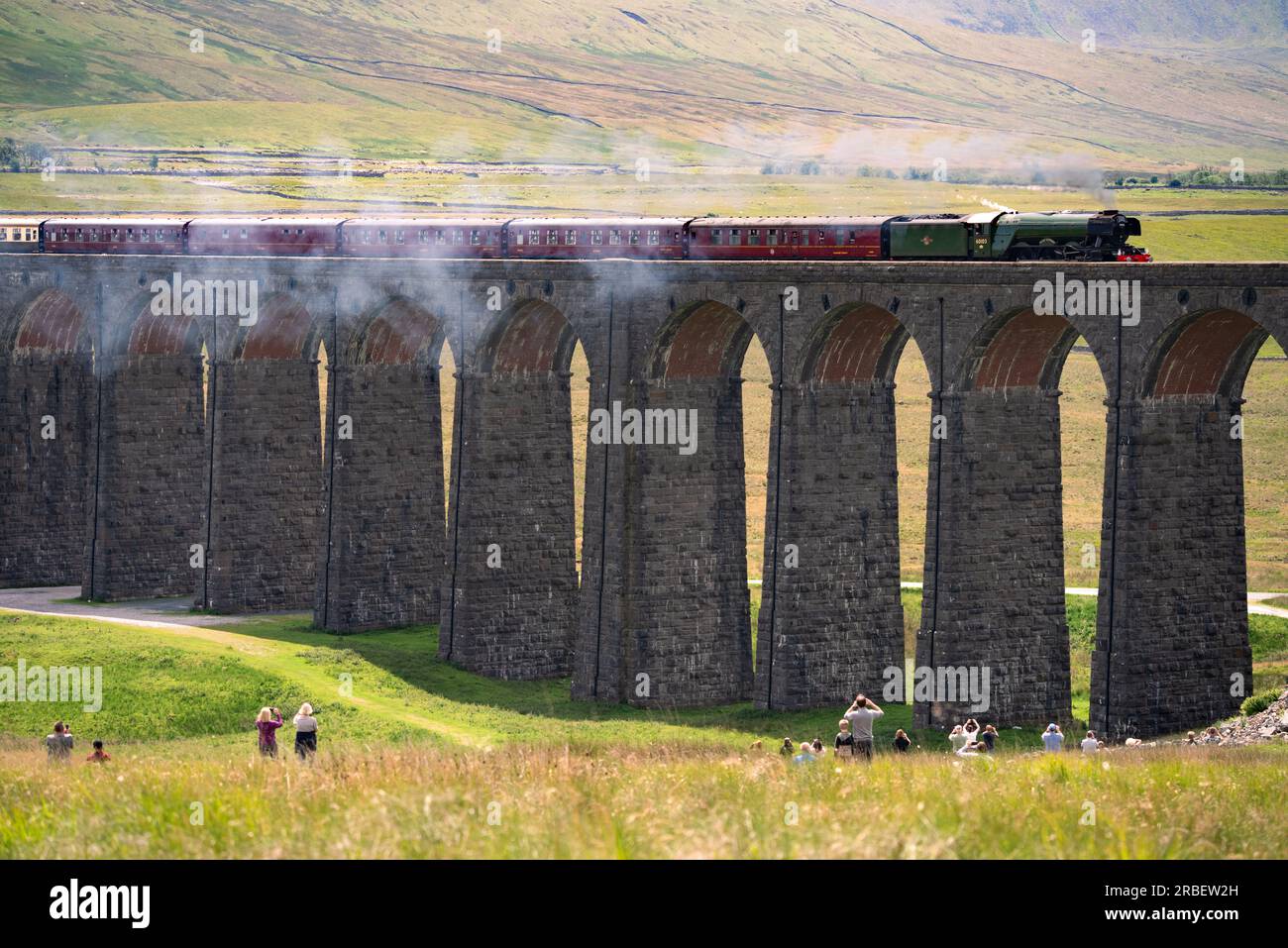 The Flying Scotsman steam train locomotive crosses The Ribblehead Viaduct as crowds of tourists spectate. Stock Photo