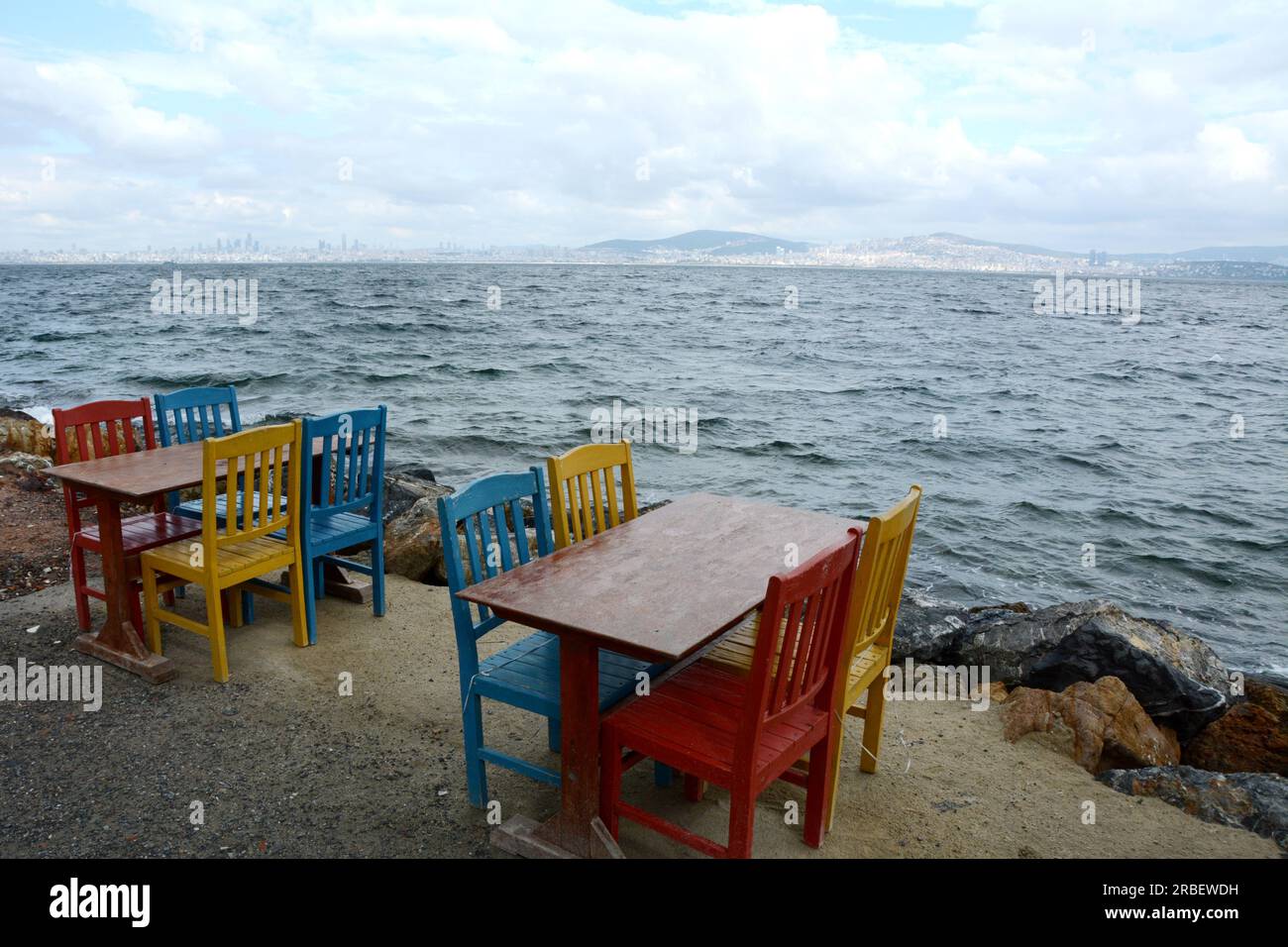 Tables and chairs at a seaside cafe on the island of Burgazada, in the Princes' Islands chain (Adalar), in the Sea of Marmara, Turkey, Turkiye. Stock Photo