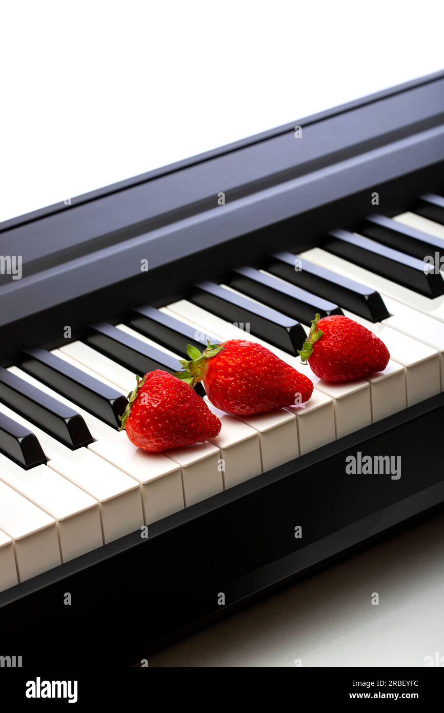 Three ripe strawberries on the piano keys Stock Photo Alamy