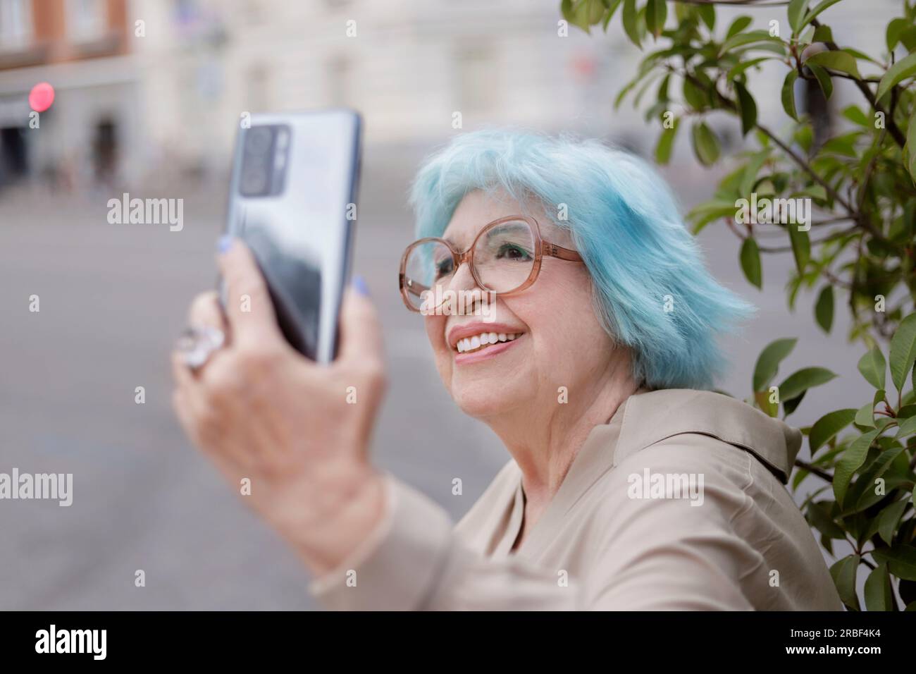 Older woman with fashionable pearl looking at her cell phone screen in the city Stock Photo